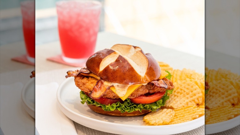 Chick-fil-A Pretzel Cheddar Club Sandwich and Waffle Potato Chips with a Cherry Berry beverage in the background
