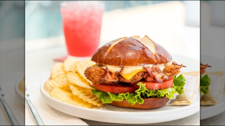 Chick-fil-A spicy Pretzel Cheddar Club Sandwich and Waffle Potato Chips with a Cherry Berry beverage in the background