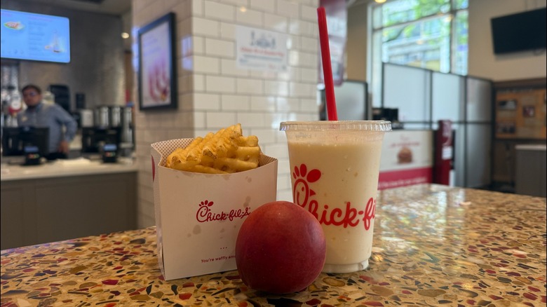Chick-fil-A Peach Frosted Lemonade with french fries and a peach