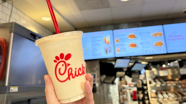 Chick-fil-A Peach Frosted Lemonade being held up in front of Chick-fil-A menu