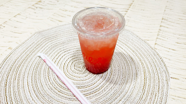 The strawberry hibiscus Sprite on a circular table mat with a straw next to it