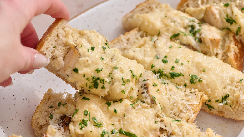 hand picking up piece of garlic bread