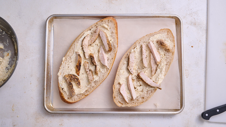 Chicken garlic bread halves on a baking sheet