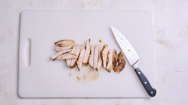 slicing chicken on a cutting board