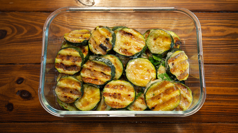 Grilled zucchini slices in a glass food container