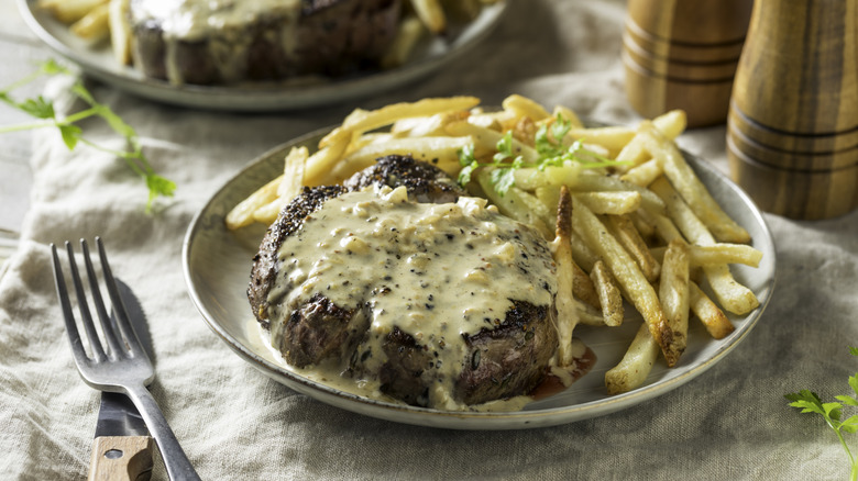 Steak au poivre with mushrooms on a white plate