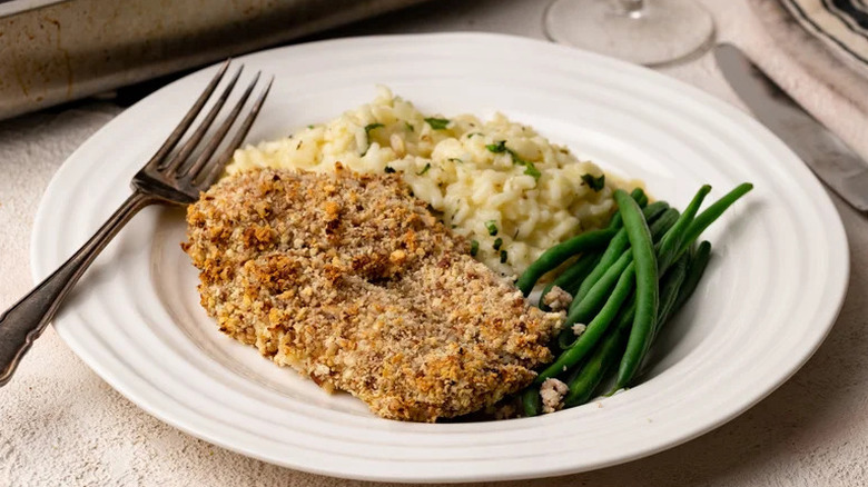 Pecan-Crusted Chicken Breasts on white plate with rice and green beans