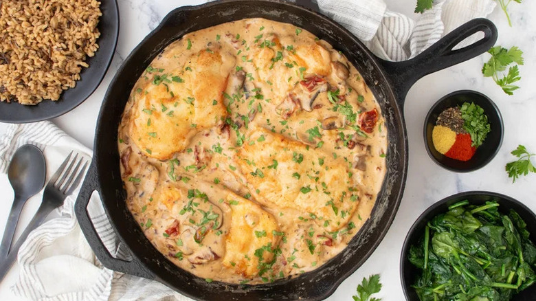 Skillet-Seared Chicken Breast with Mushroom Sauce in black skillet with other dishes