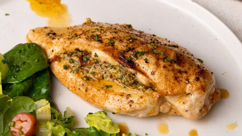 Spinach and Tomato-Stuffed Chicken Breast on white plate with salad