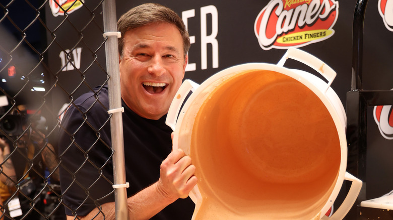A chef dumps Raising Cane's sauce from a large bucket.