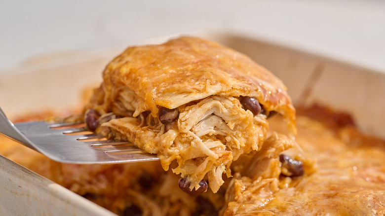 lifting a slice of enchilada casserole out of a dish