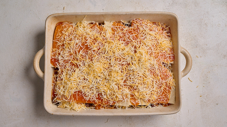 tortillas, sauce, and cheese layered into casserole dish