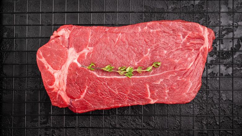 Whole raw top sirloin steak with single piece of thyme