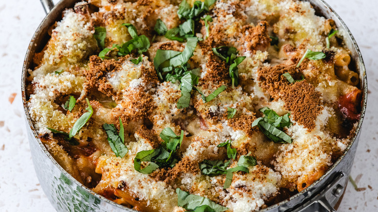 Chicken parmesan baked ziti with fresh basil in a pan