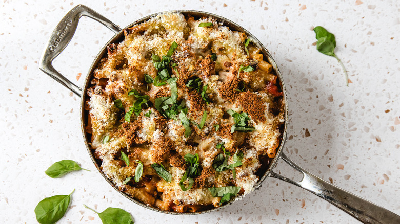 Chicken parmesan baked ziti with fresh basil in a pan