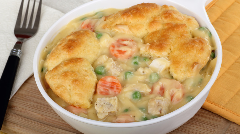 A chicken pot pie with a biscuit crust in a white baking dish