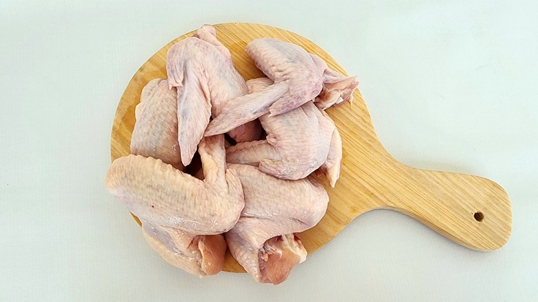 Raw whole chicken wings on a wooden board