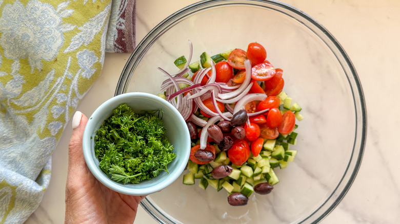 hand adding parsley to salad