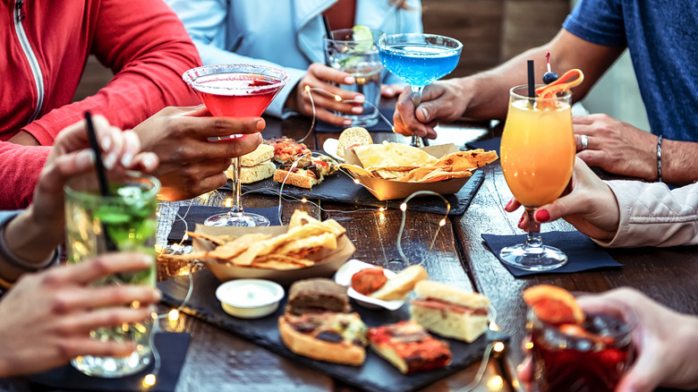 Group of friends enjoying a happy hour with drinks and food on the table