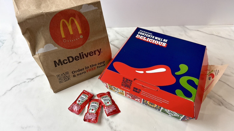 McDonald's to-go bag aside a Chili's to-go cardboard container with 3 ketchup packets