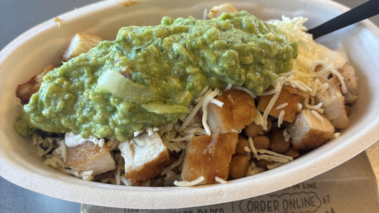 a Chipotle burrito bowl showing the new crispy chicken topped with cheese and guacamole