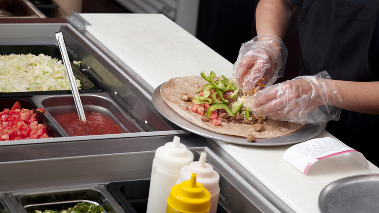 a cook making a mission-style burrito at Chipotle
