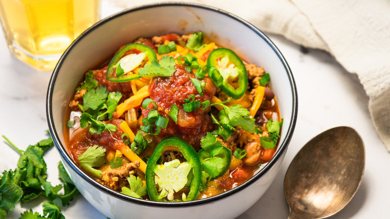 One serving of turkey chili alongside beer glass.