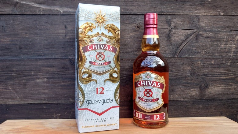 A bottle of Chivas Regal 12-year and its box presented against a wooden background
