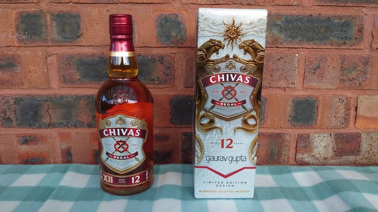 A bottle of Chivas Regal 12-year and its box presented in front of a brick background