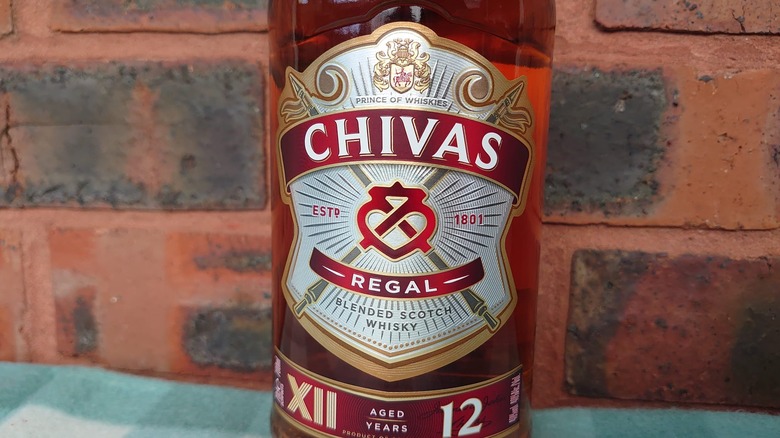 A close up of the Chivas Regal 12-year bottle label against a red brick background