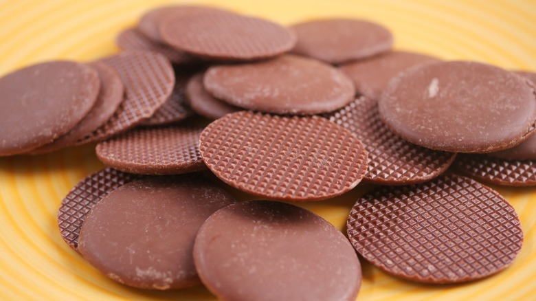 A pile of chocolate discs on a yellow plate