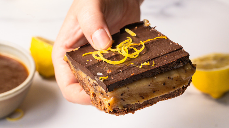Hand holding a chocolate lemon bar slice