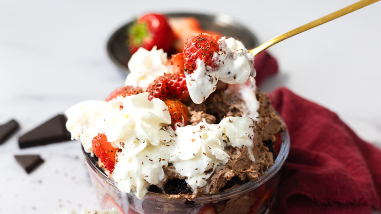 Lifting a spoonful of chocolate strawberry trifle
