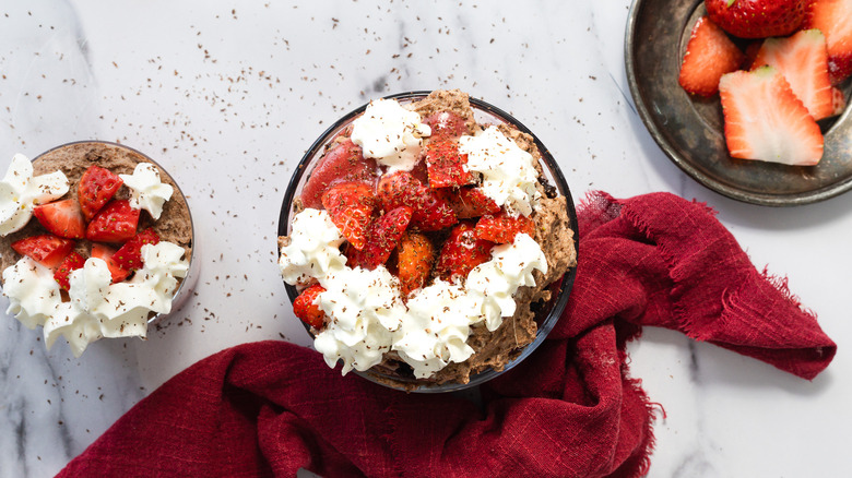 Two servings of chocolate strawberry trifle with strawberries on the side.