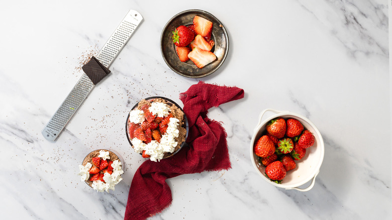 Two servings of chocolate strawberry trifle with strawberries on the side.