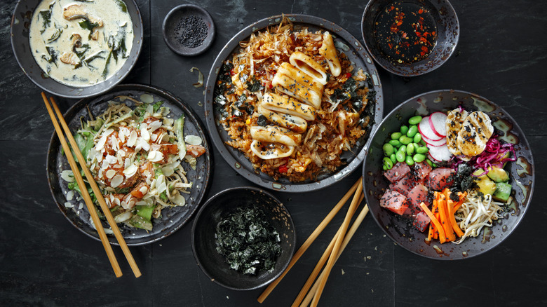 A variety of Japanese dishes and sets of chopsticks on a table