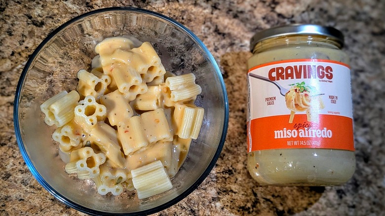 Cravings by Chrissy Teigen Spicy Miso Alfredo pasta sauce on pasta next to jar