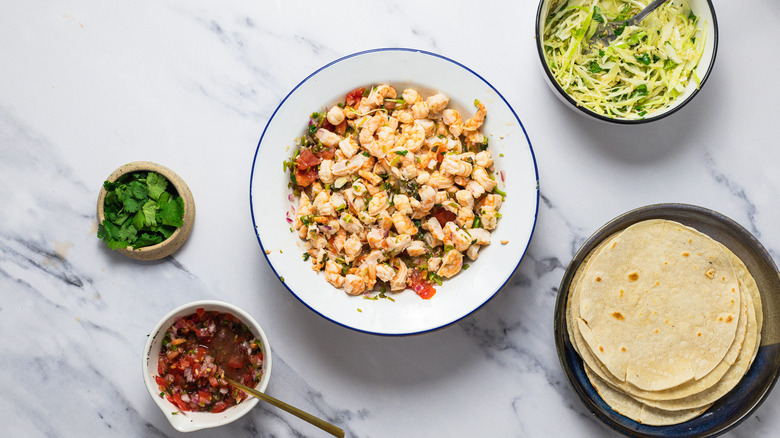 Cooked shrimp in bowl with other components around.