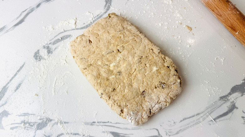 Rectangular biscuit dough on floured countertop