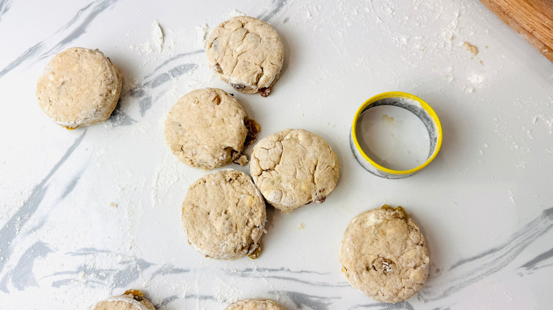 Cut out biscuits with biscuit cutter on countertop