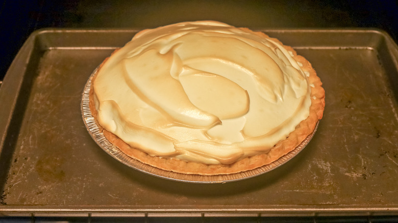 meringue-topped pie on a baking pan in an oven