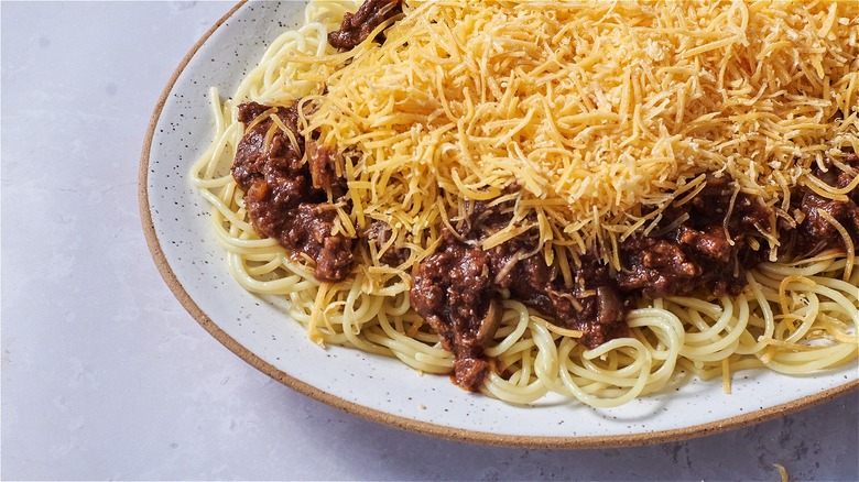 plate of chili on spaghetti with cheese