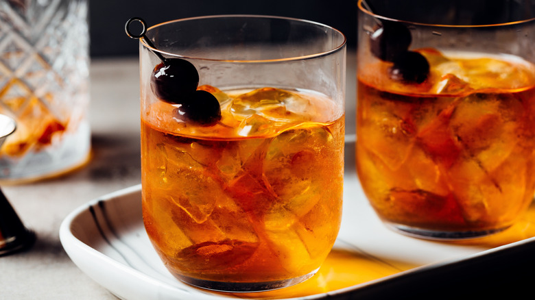 Two Manhattan cocktails with ice on white tray
