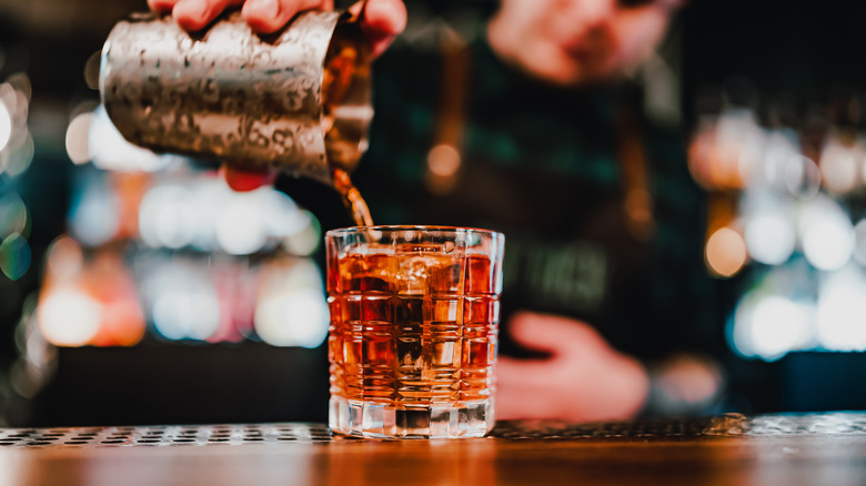 Blurred bartender pouring a Negroni or Boulevardier