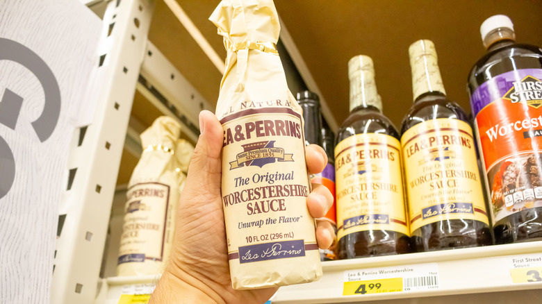 hand holds up wrapped bottle of Lea & Perrins sauce in grocery aisle
