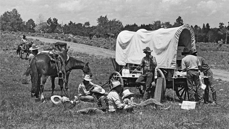 Ranch cowboys gather around a chuck wagon fora quick lunch on the go during a cattle drive