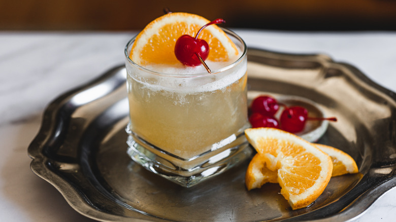 whiskey sour on metal tray with garnishes