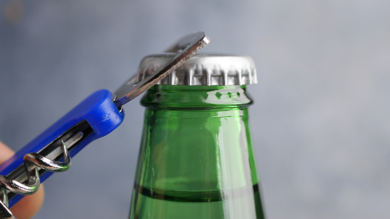 Green glass soda bottle being opened