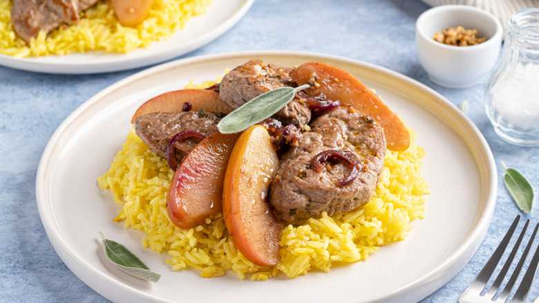 pork chops with baked apple slices on white plate with rice