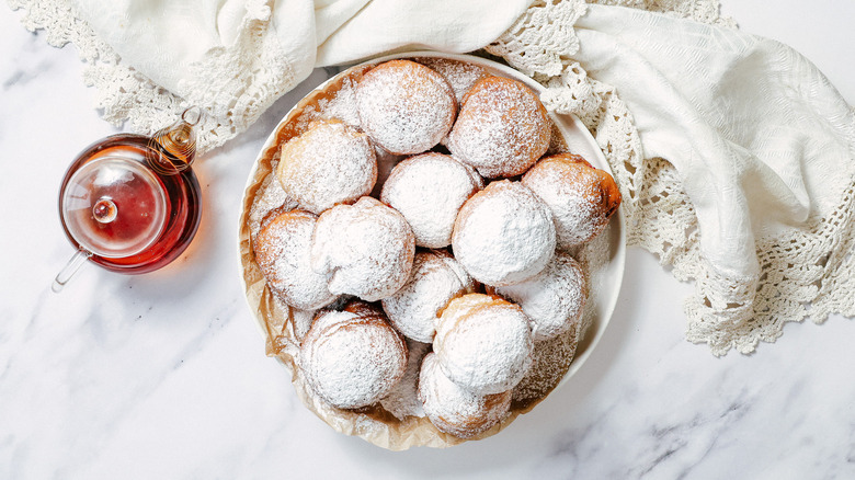 Plate full of raspberry sufganiyot with teapot besides them